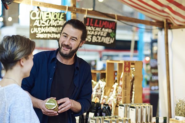 Foto von Reza Zand bei einem Gespräch am Verkaufsstand mit einer Kundin